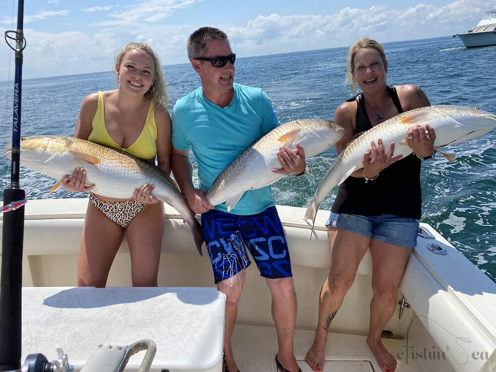 Happy campers holding up their huge Red Drum